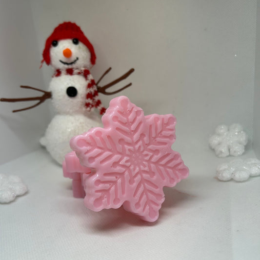 Pink snowflake-shaped soap in front of a snowman, perfect for winter skincare and holiday gift sets.